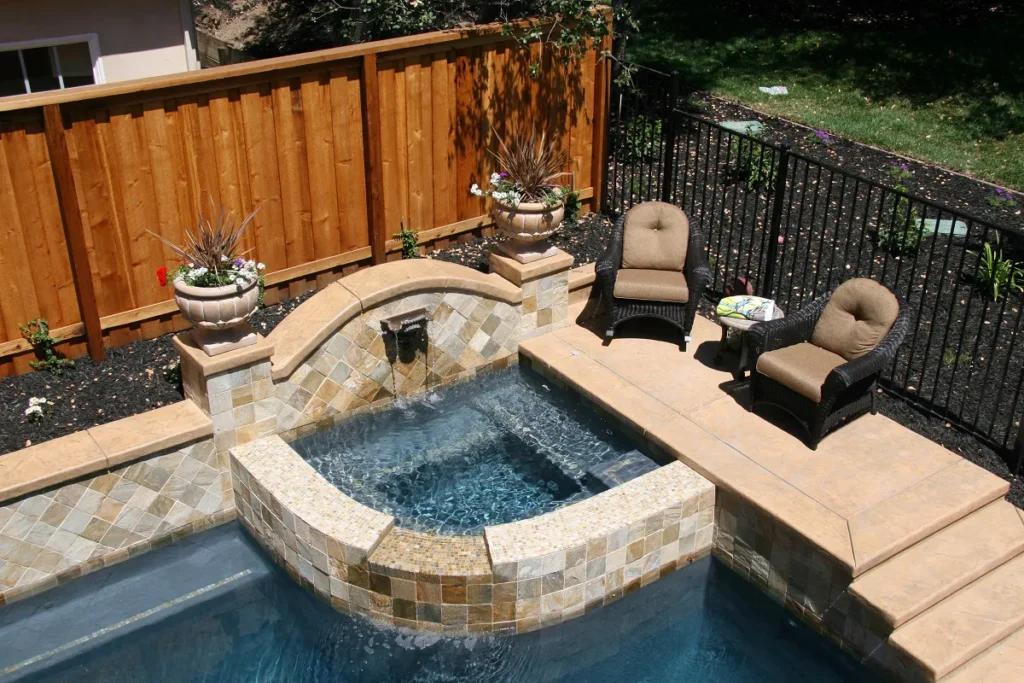 Tuscany-style raised gunite spa featuring natural stone masonry, a custom spillway, and integrated bench seating.