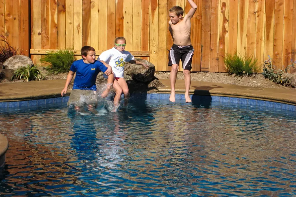 Children jumping into a custom backyard gunite pool