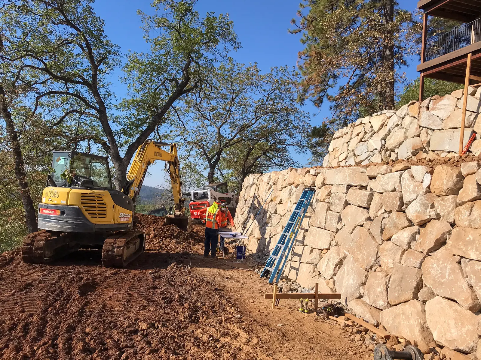 Engineered retaining wall system stabilizing a steep hillside during vanishing edge pool construction in Colfax California