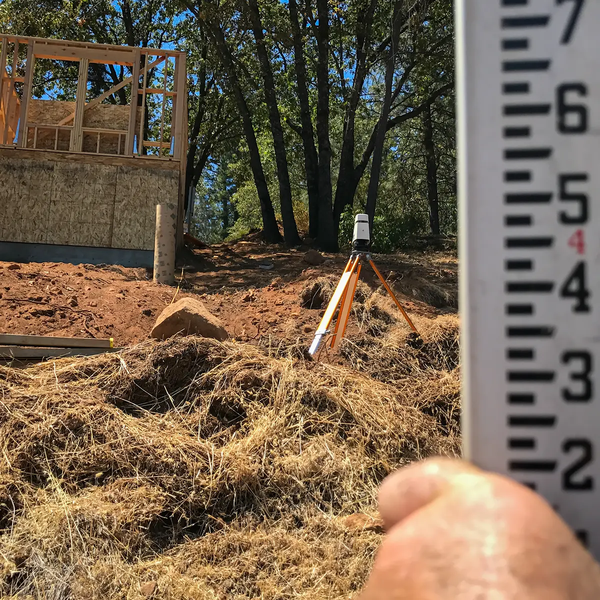Laser surveying equipment measuring elevation on a steep residential hillside in Colfax prior to swimming pool construction