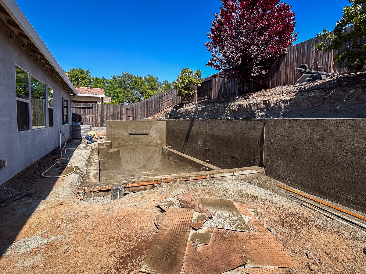 Completed gunite pool shell and structural retaining wall after two-day shoot on small yard hillside site in Rocklin CA