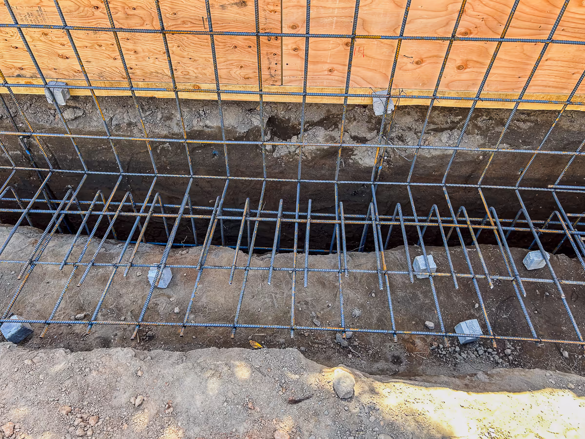 Retaining wall footing rebar cage with hooked dowels and Dobie concrete bricks for small yard pool construction in Rocklin CA