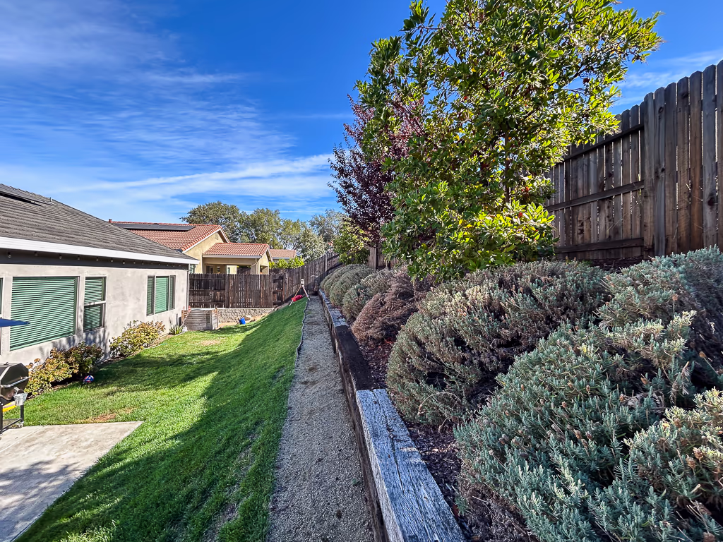 Full length of backyard at Rocklin property showing slope and limited access for pool construction