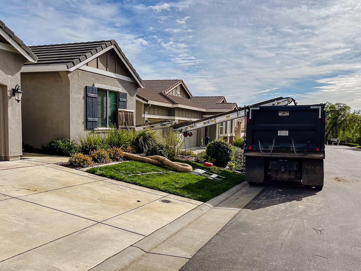 Dump truck staged at curb receiving soil from conveyor during pool excavation in Rocklin CA