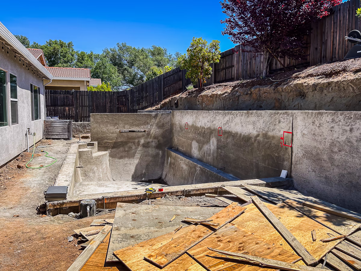 Custom gunite pool in Rocklin California after form removal with decorative tile layout templates marked on retaining wall