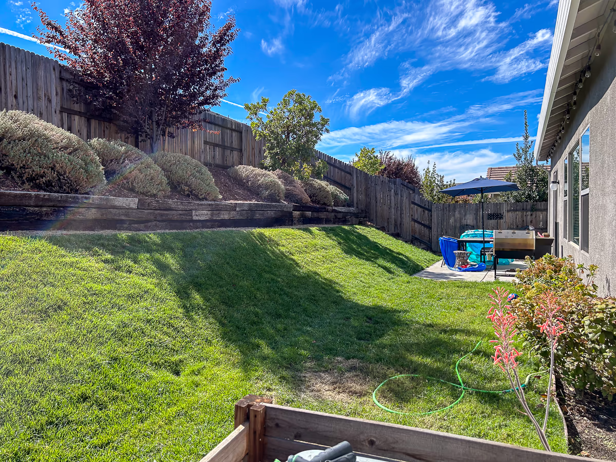 Steep backyard slope with existing retaining walls before custom pool construction in Rocklin California