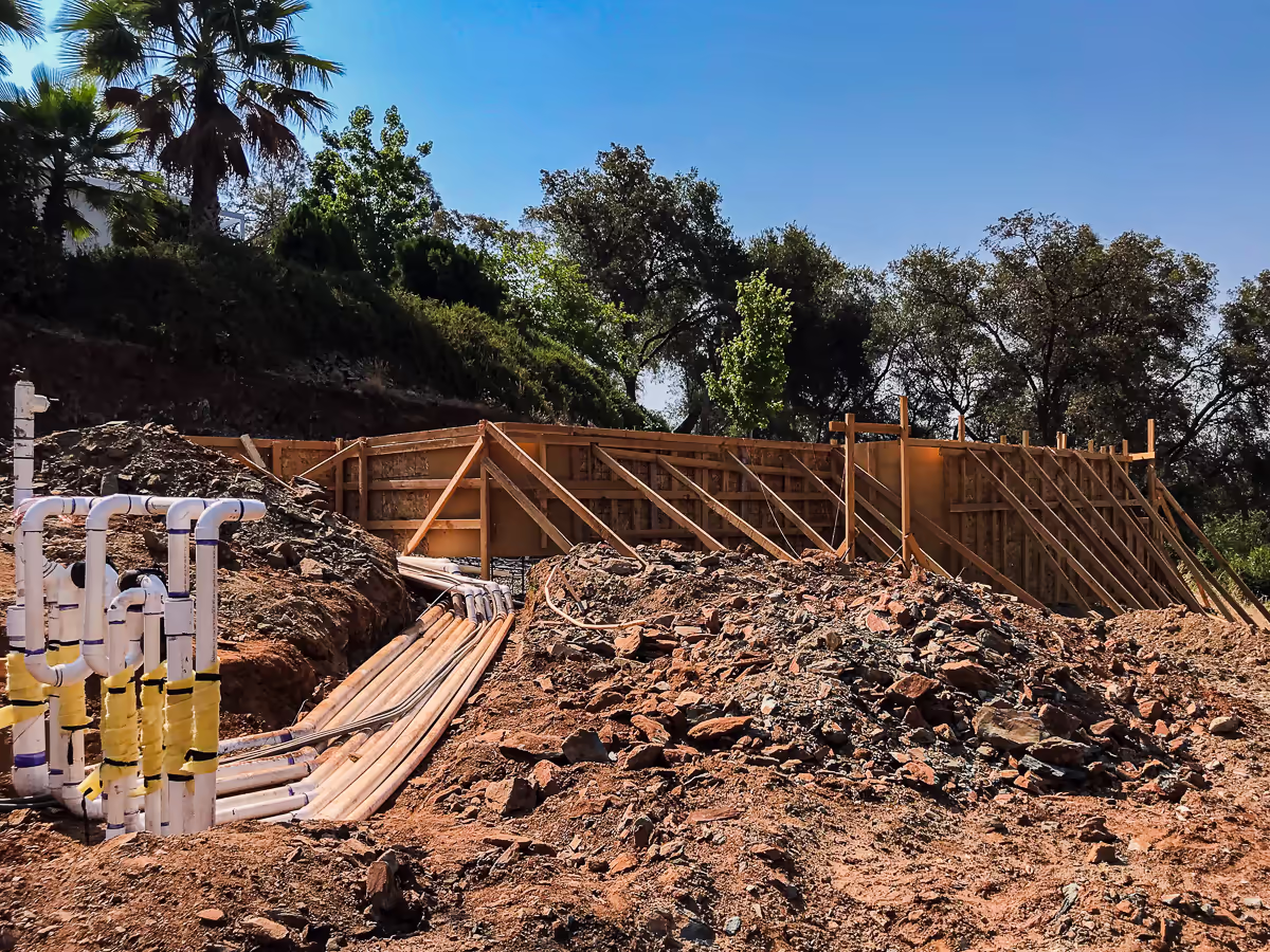 Freestanding wall bracing and plumbing rough-in on the downslope face of an Auburn hillside vanishing edge pool — Jim Chandler Pools