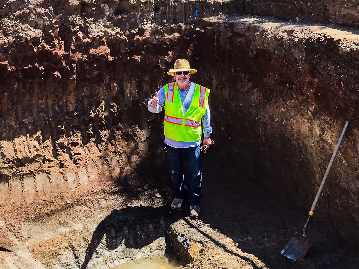 Jim Chandler inspecting finish depth and groundwater conditions inside a custom pool excavation