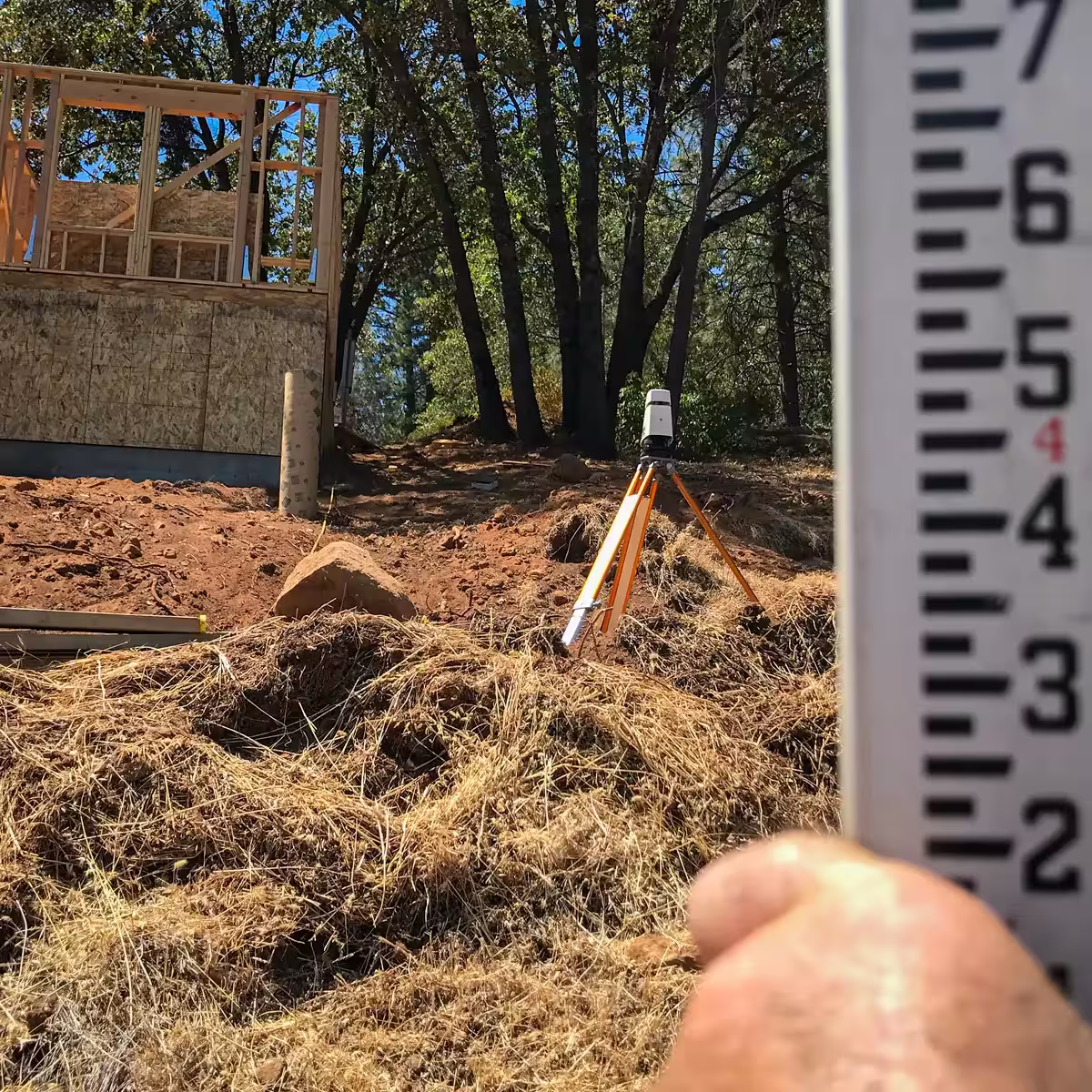 Laser level surveying on steep Colfax hillside — measuring 25-foot grade change for vanishing edge pool construction by Jim Chandler Pools