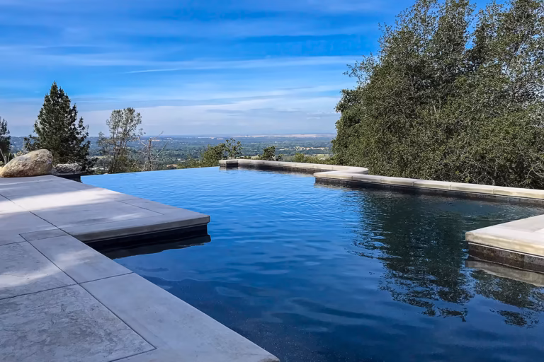 Completed Auburn vanishing edge pool with dark interior finish reflecting the sky following startup and final water balancing